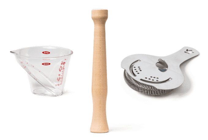 from left to right, a clear plastic jigger that resembles a liquid measuring cup, a wooden muddler, and a Hawthorne strainer 