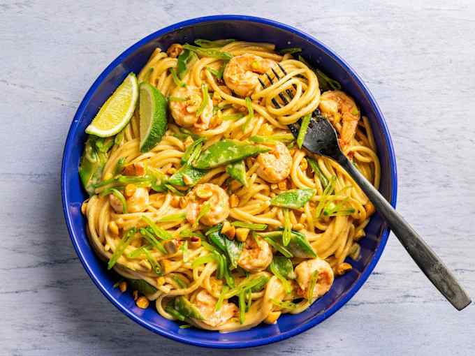 A bowl of spicy peanut noodles with a fork in it.