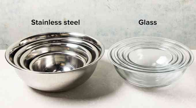 A set of stainless steel mixing bowls next to a set of glass mixing bowls.