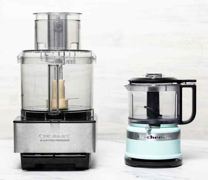 A large silver food processor next to a smaller turquoise food processor.