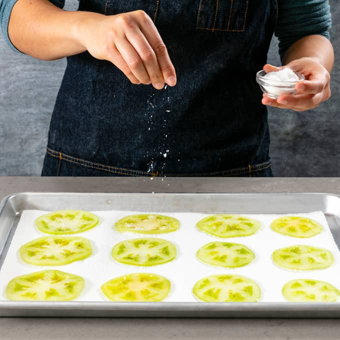 Sprinkling fried green tomatoes with sugar and salt