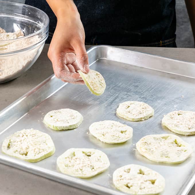 Placing floured green tomatoes on a baking sheet