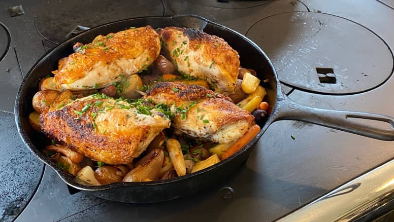 finished chicken and root vegetables in cast iron skillet