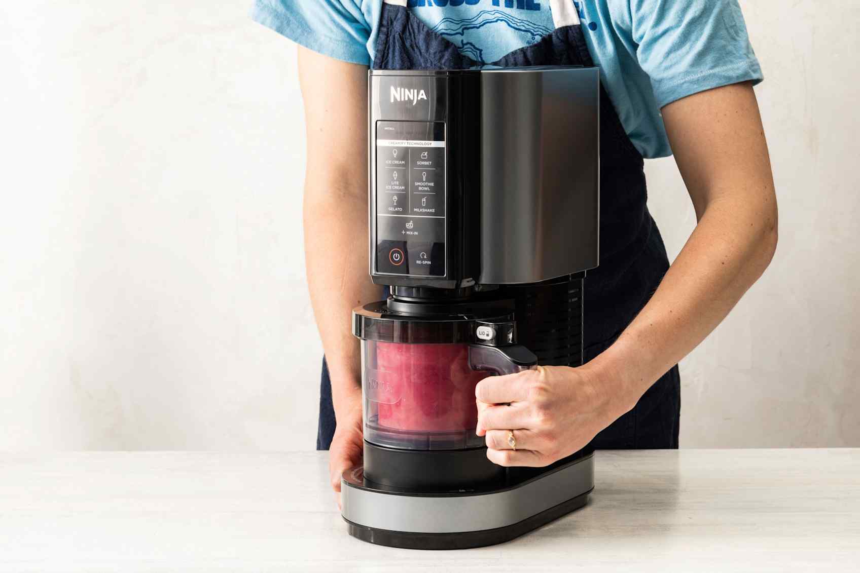 Person inserting container into a black ice cream maker.