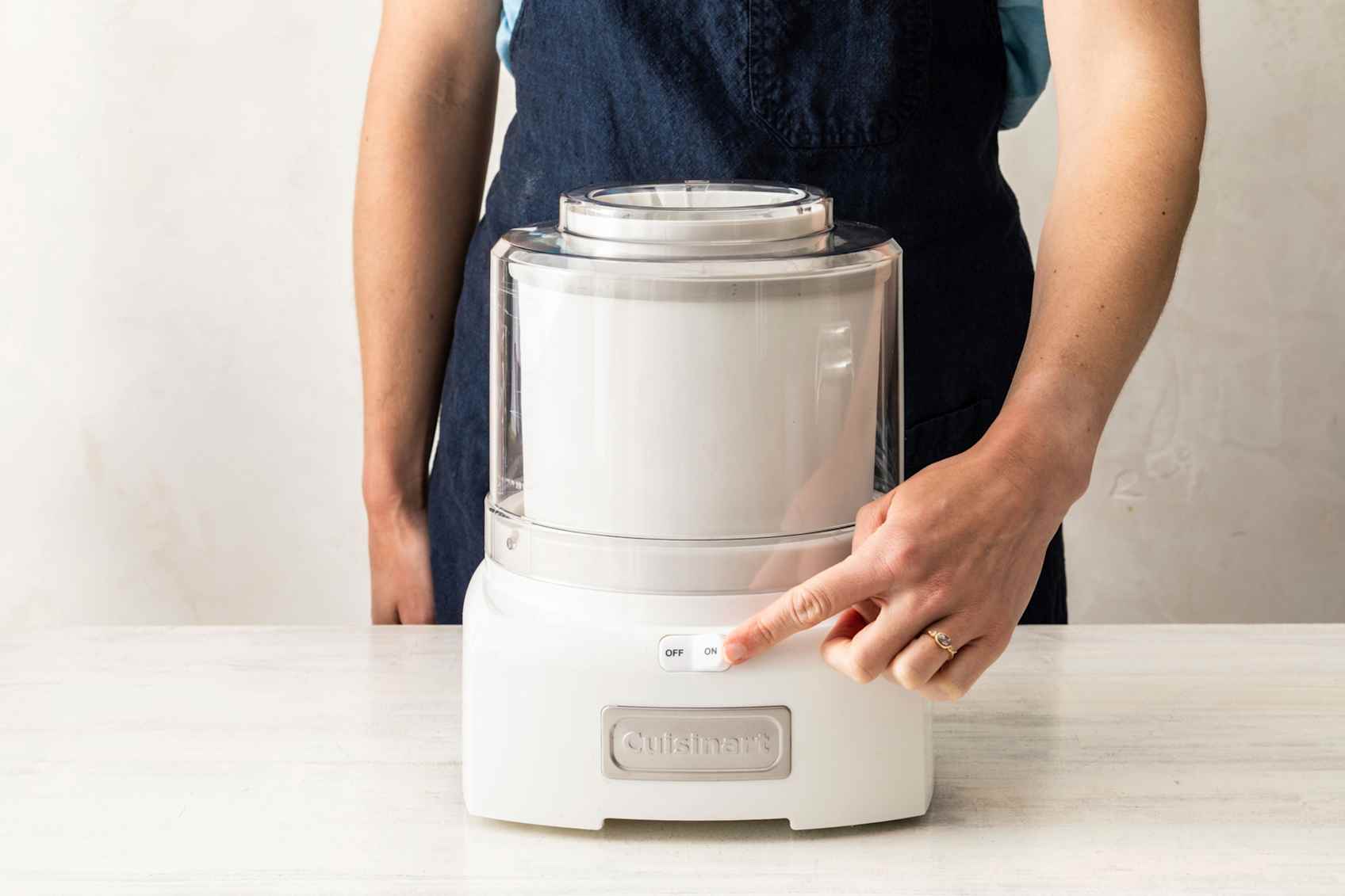 Person pressing the on button of a white ice cream making.