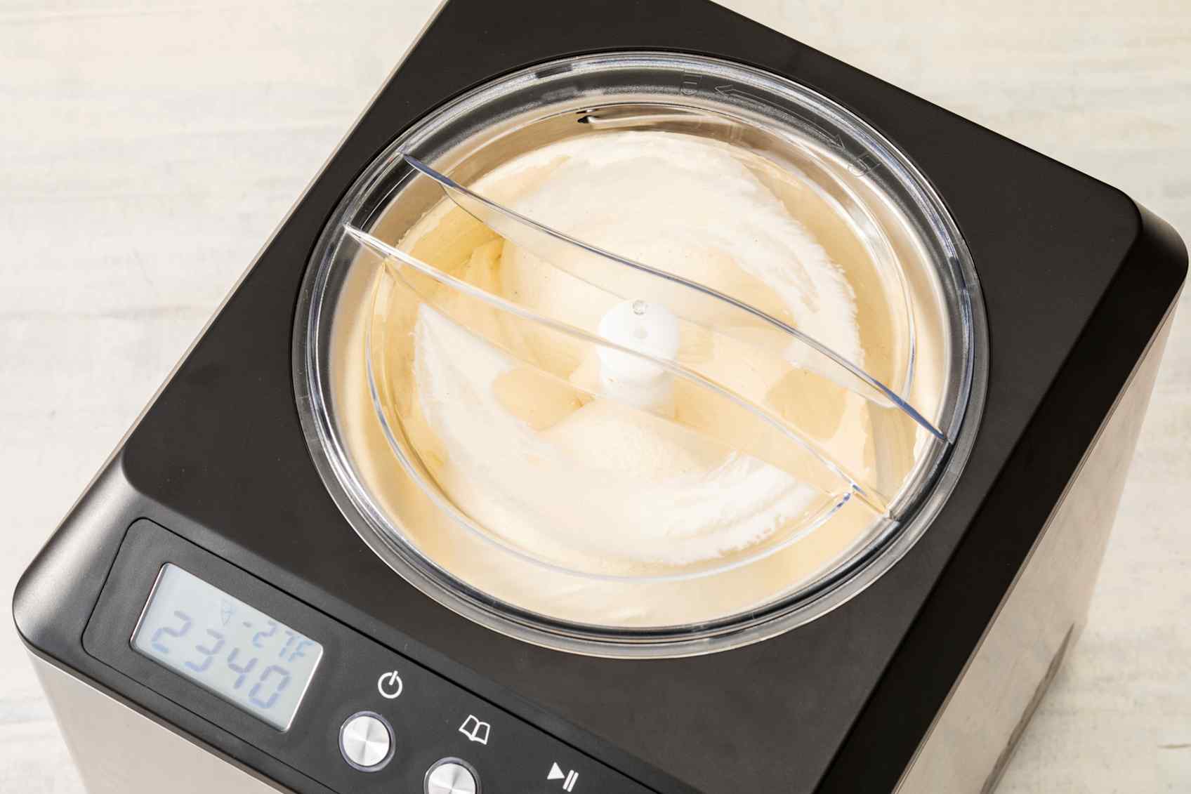 Vanilla ice cream churning in a silver and black ice cream maker.