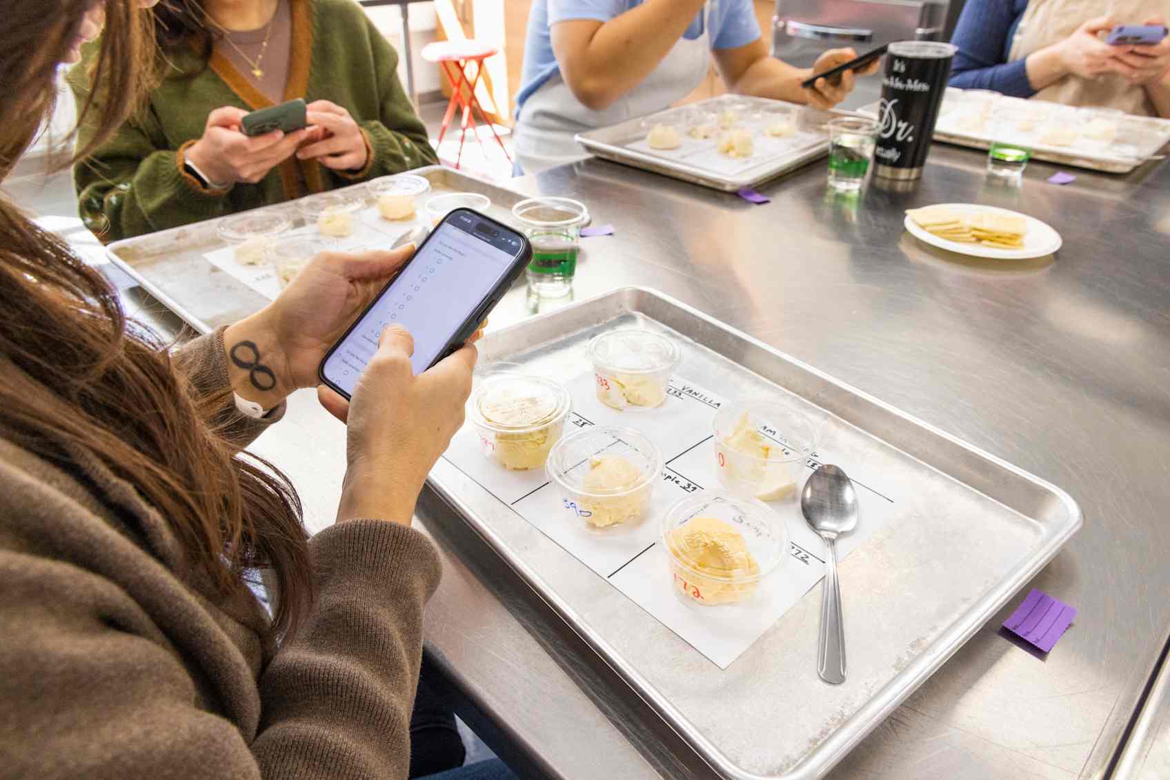 Taster with tray of samples in front of them using their phone to fill out a survey.