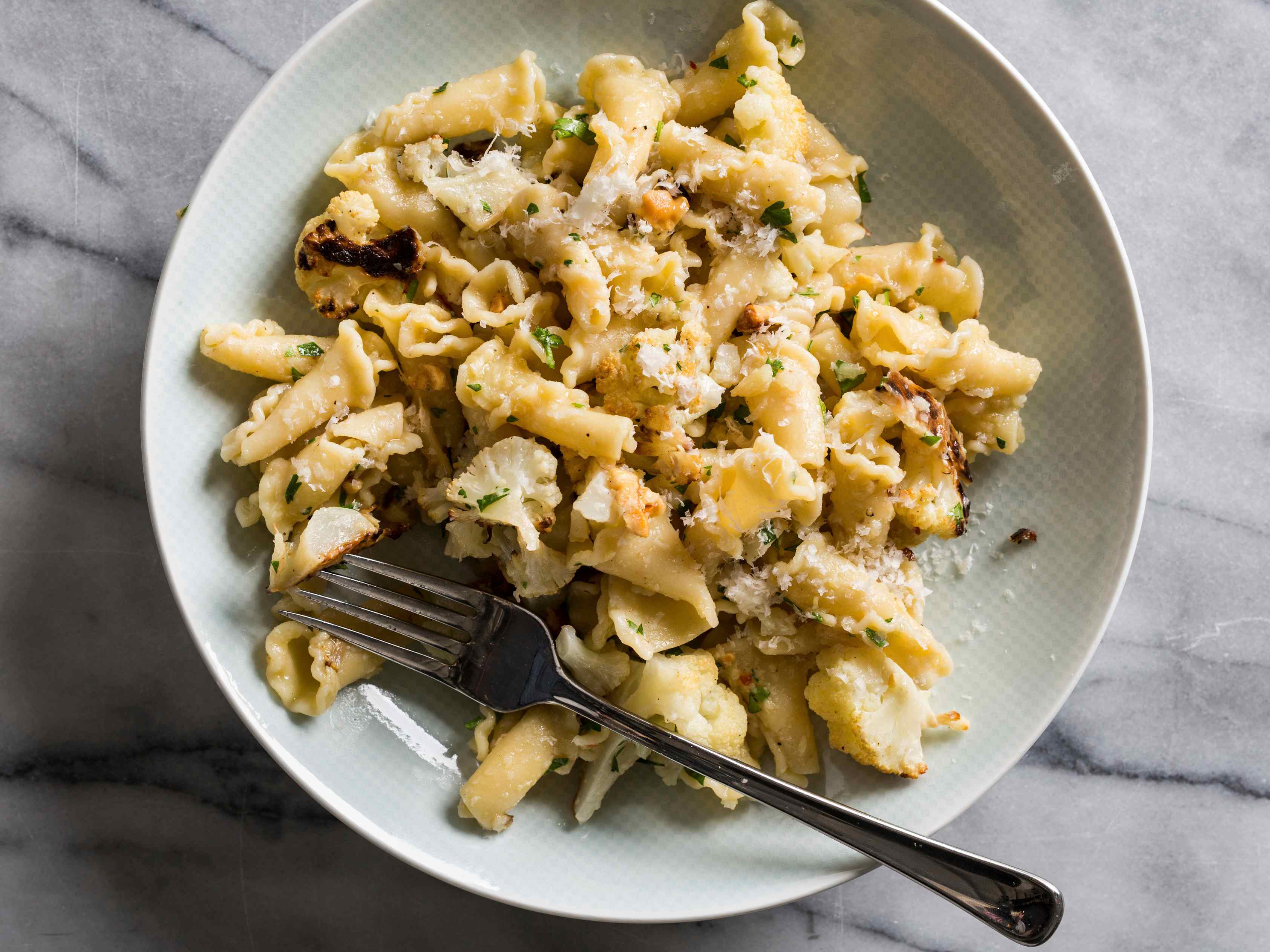 Pasta with Roasted Cauliflower, Garlic, and Walnuts and a fork along the bottom of the white bowl