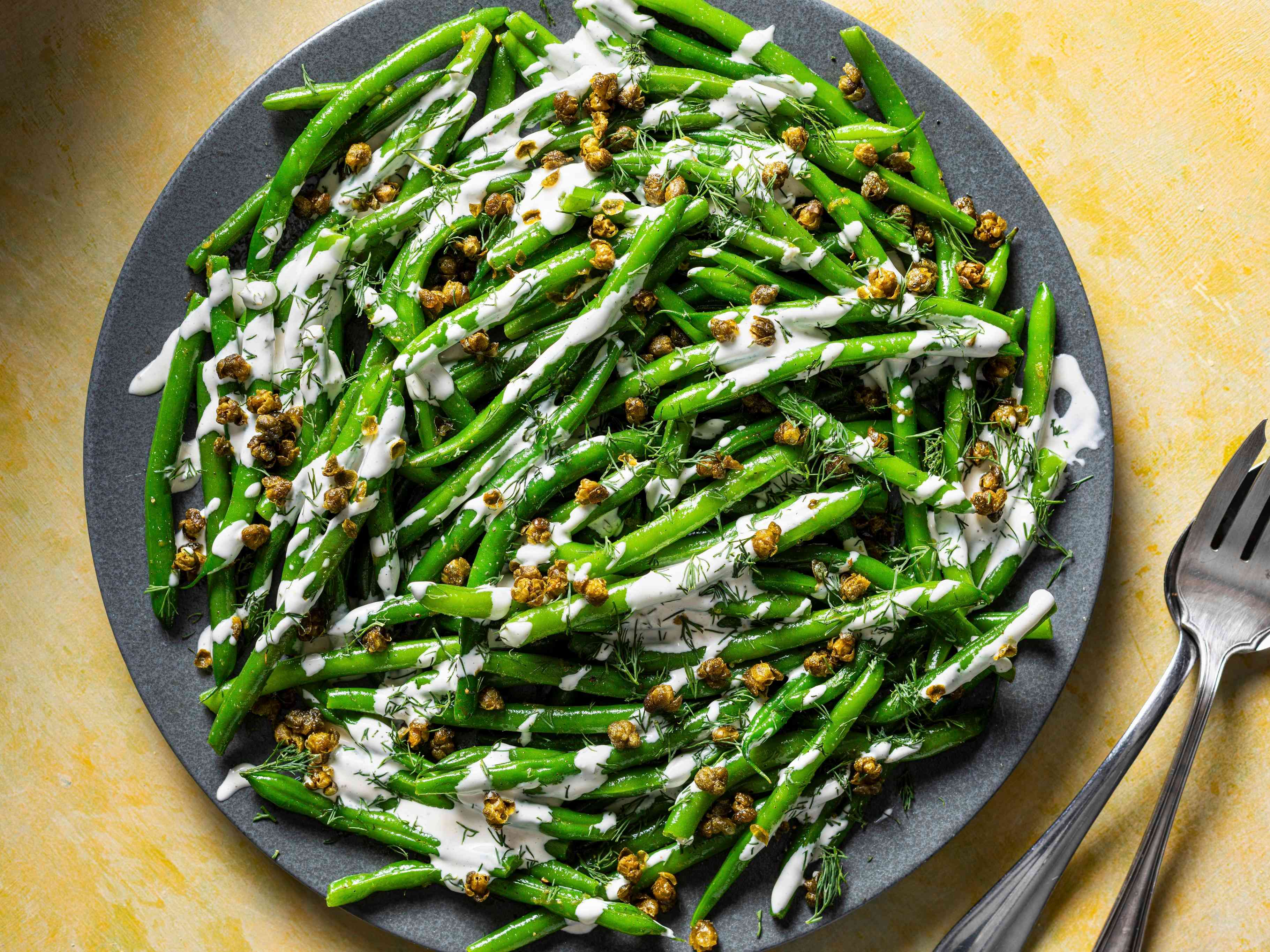 Close-up of green beans drizzled with creamy lemon sauce and sprinkled with crispy capers and dill