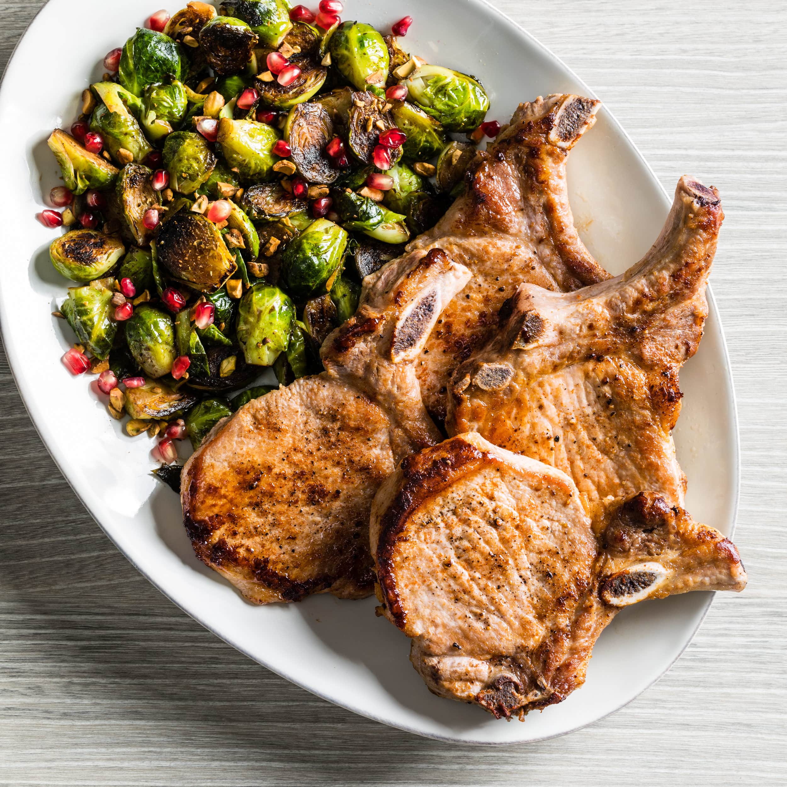 Pan-Seared Pork Chops with Blistered Brussels Sprouts and Pomegranate | America's Test Kitchen
