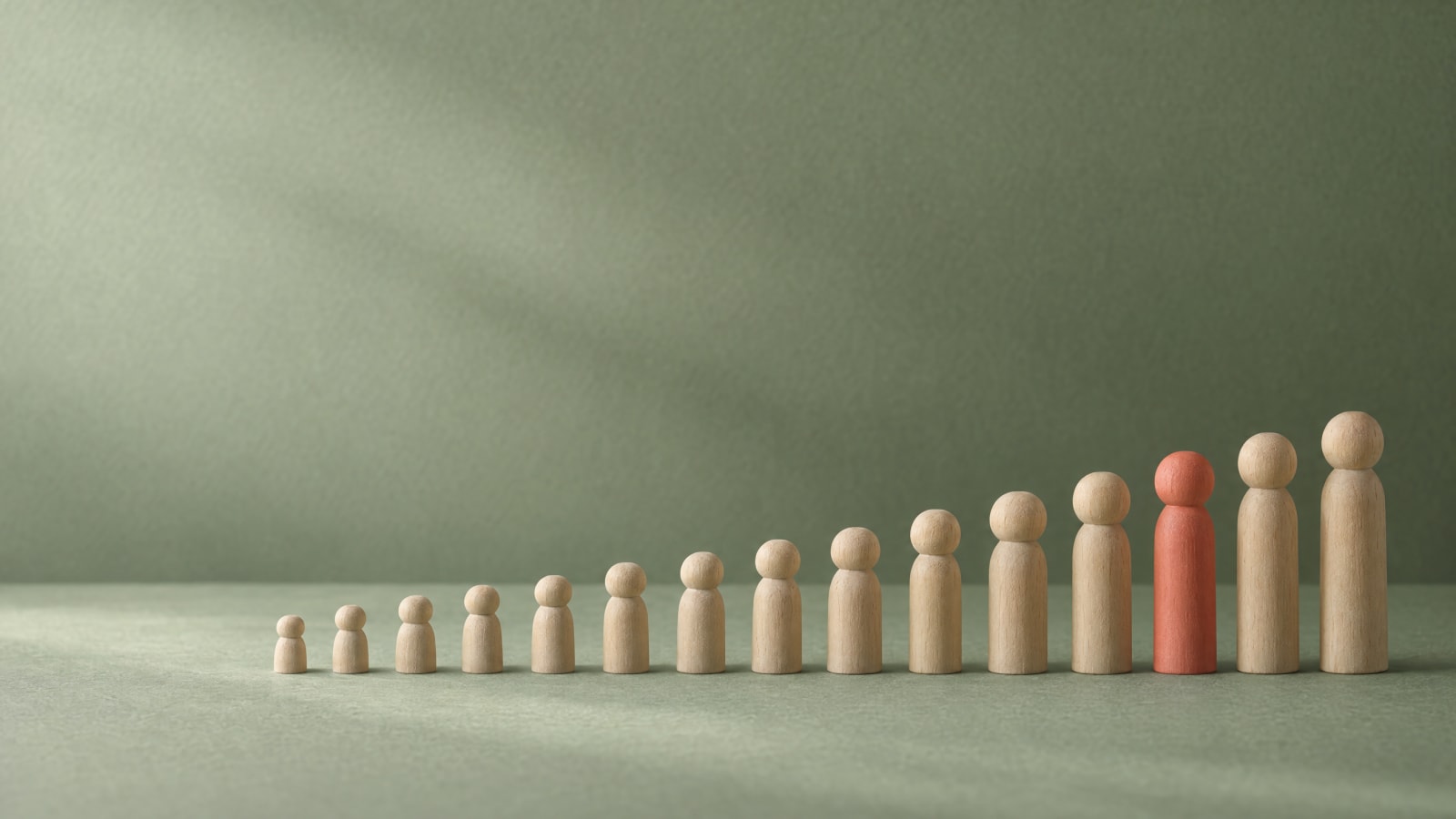 A row of rising wooden pegs with one painted peg.