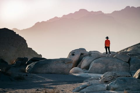 A traveller standing on rocks above the hills at dusk