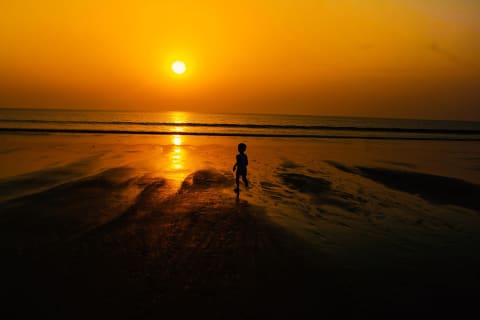 A child running on Kuakata beach at sunset