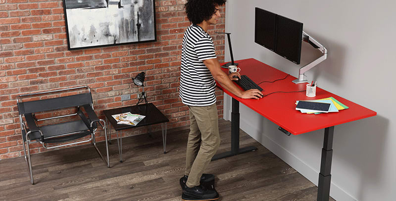 Man working from home standing at SmartMoves Adjustable Height Desk