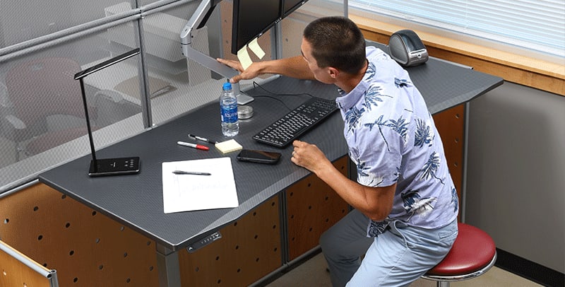 Man adjusting monitor arm at SmartMoves Adjustable Height Desk