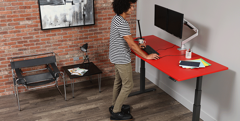 Man working from home standing at SmartMoves Adjustable Height Desk