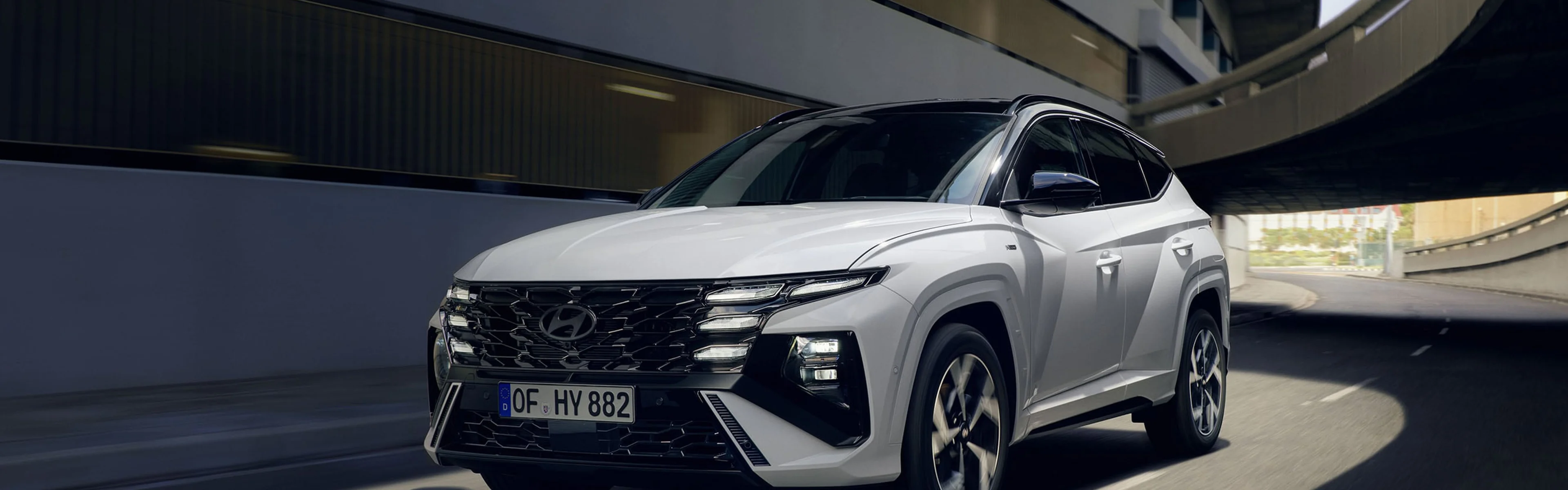 Ein Mann blickt zurück auf seinen Hyundai TUCSON, der vor einem modernen Wohnbungalow parkt.