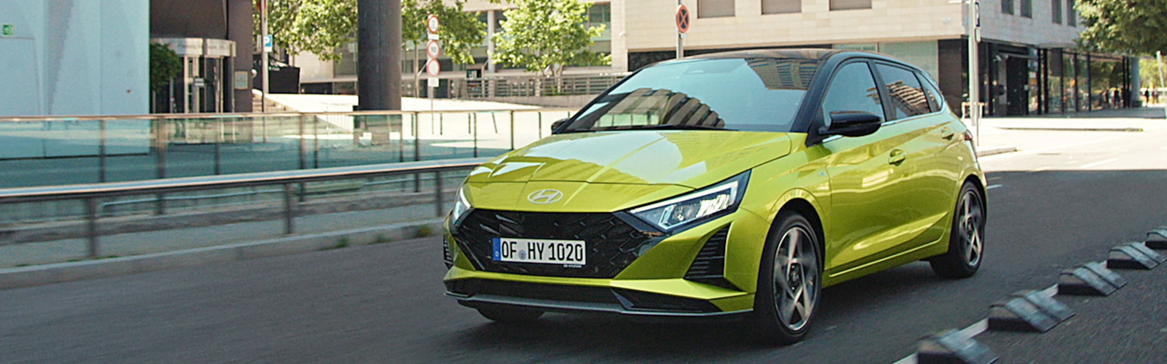 Ein Hyundai i20 fährt eine Straße entlang mit Gebäuden im Hintergrund.