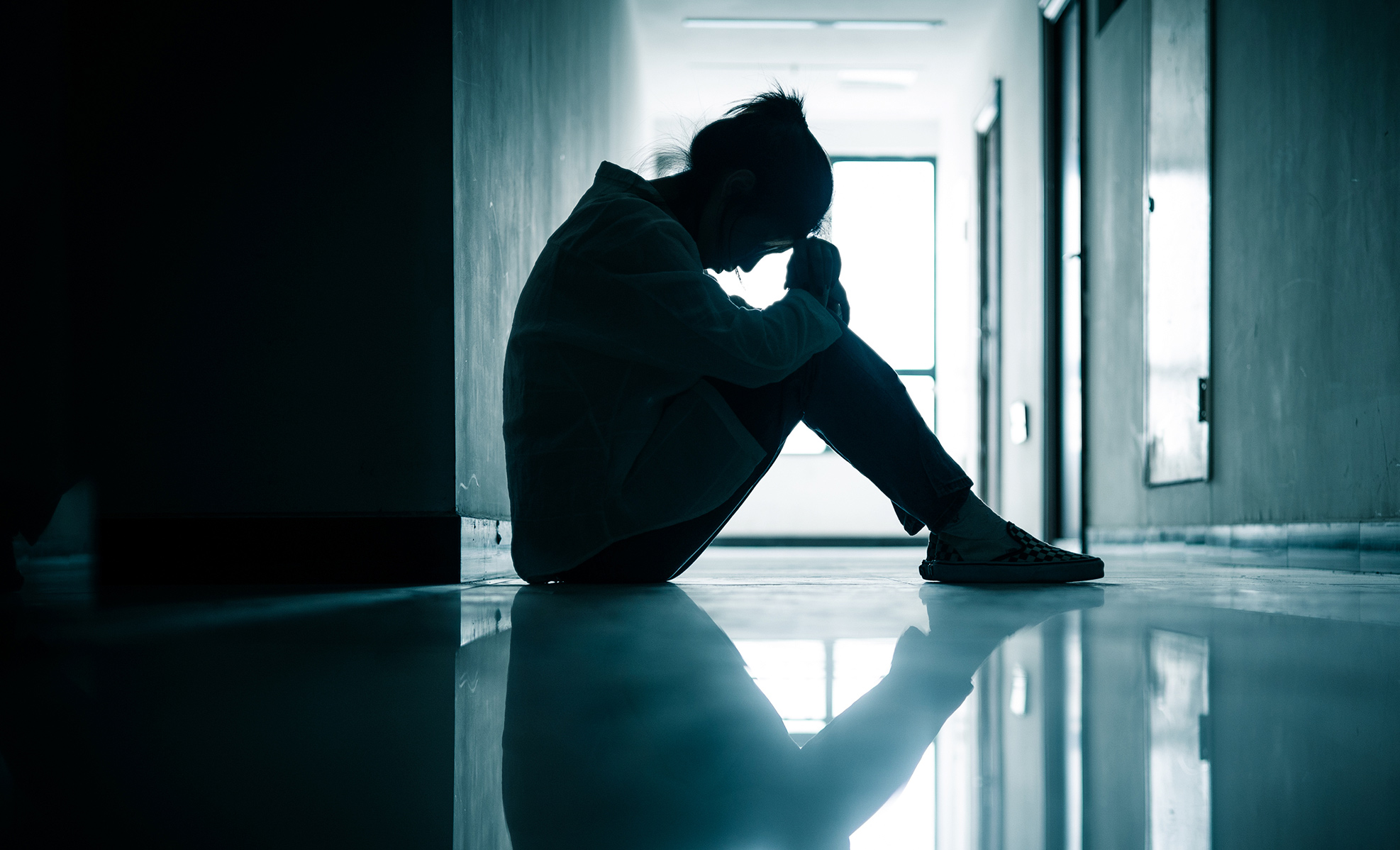 teen sitting in hallway depressed