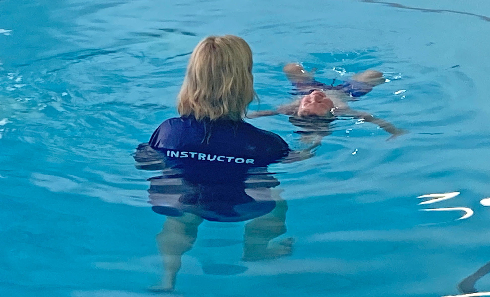 swim instructor teaching a child how to float