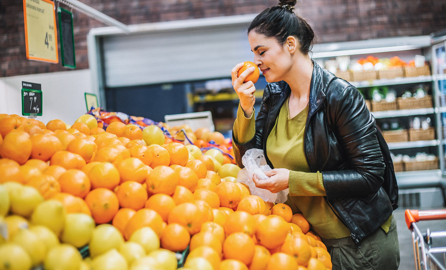 woman smelling oranges while shopping for groceries