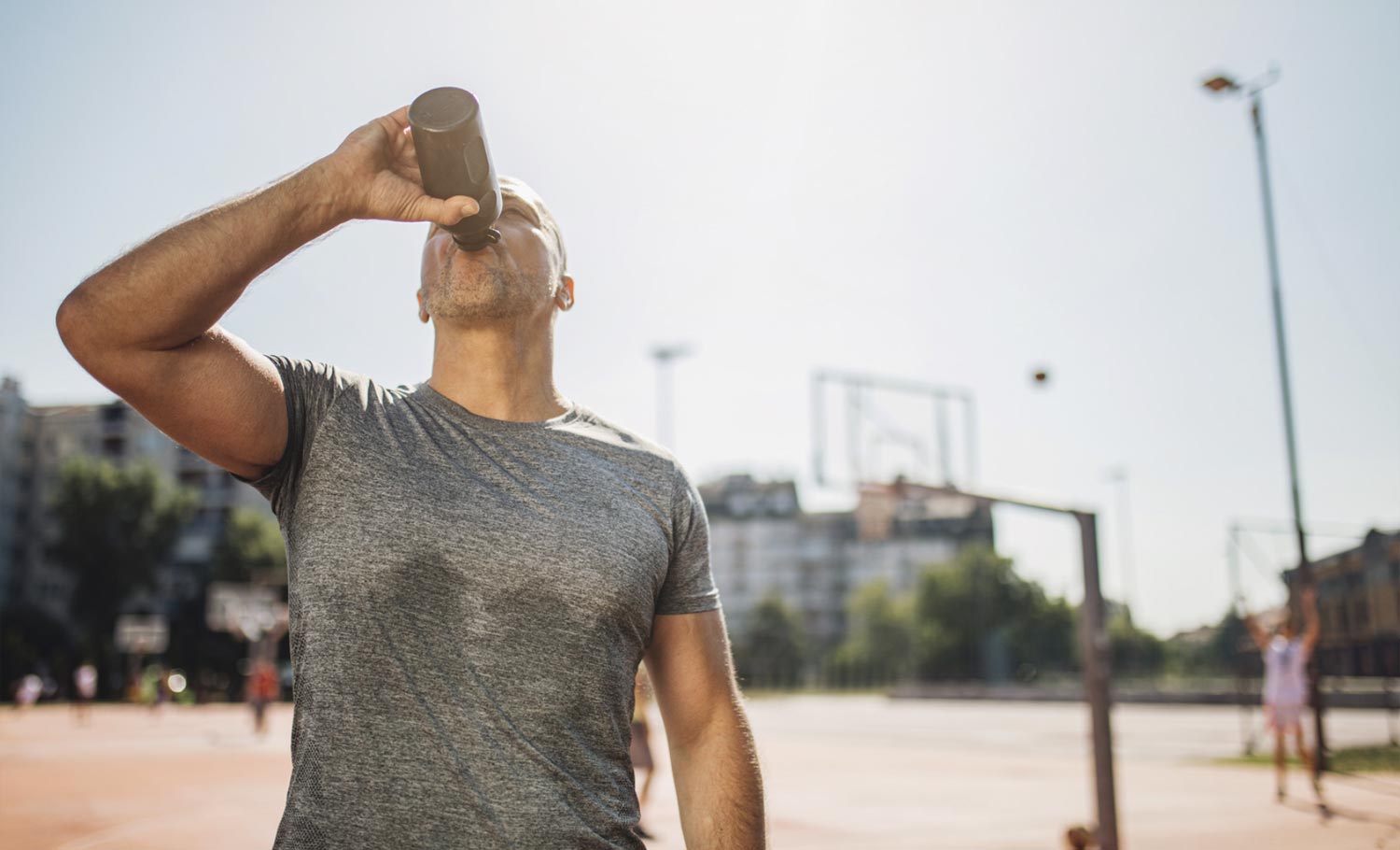 man drinking a sports drink while playing basketball