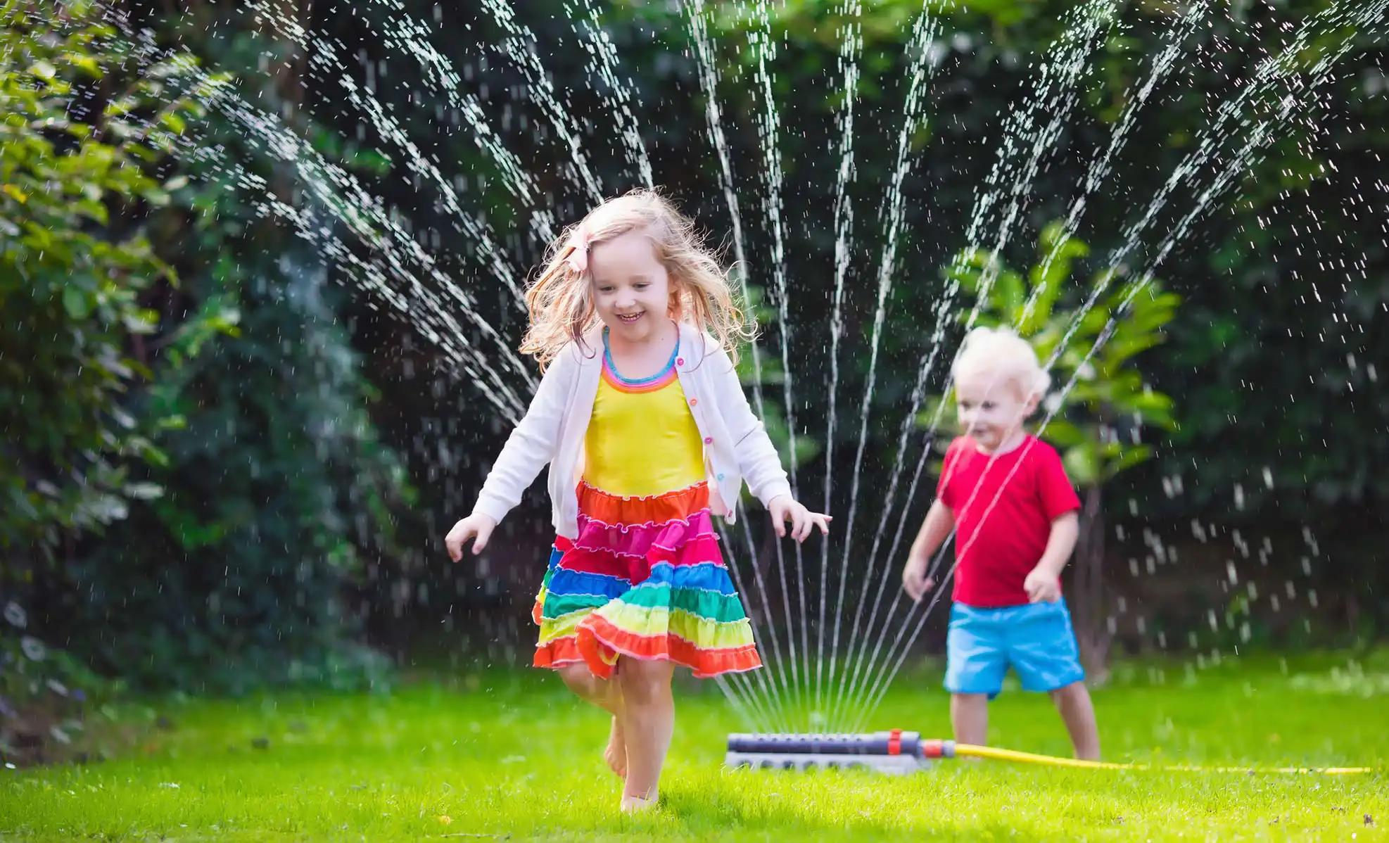 kids running through a sprinkler