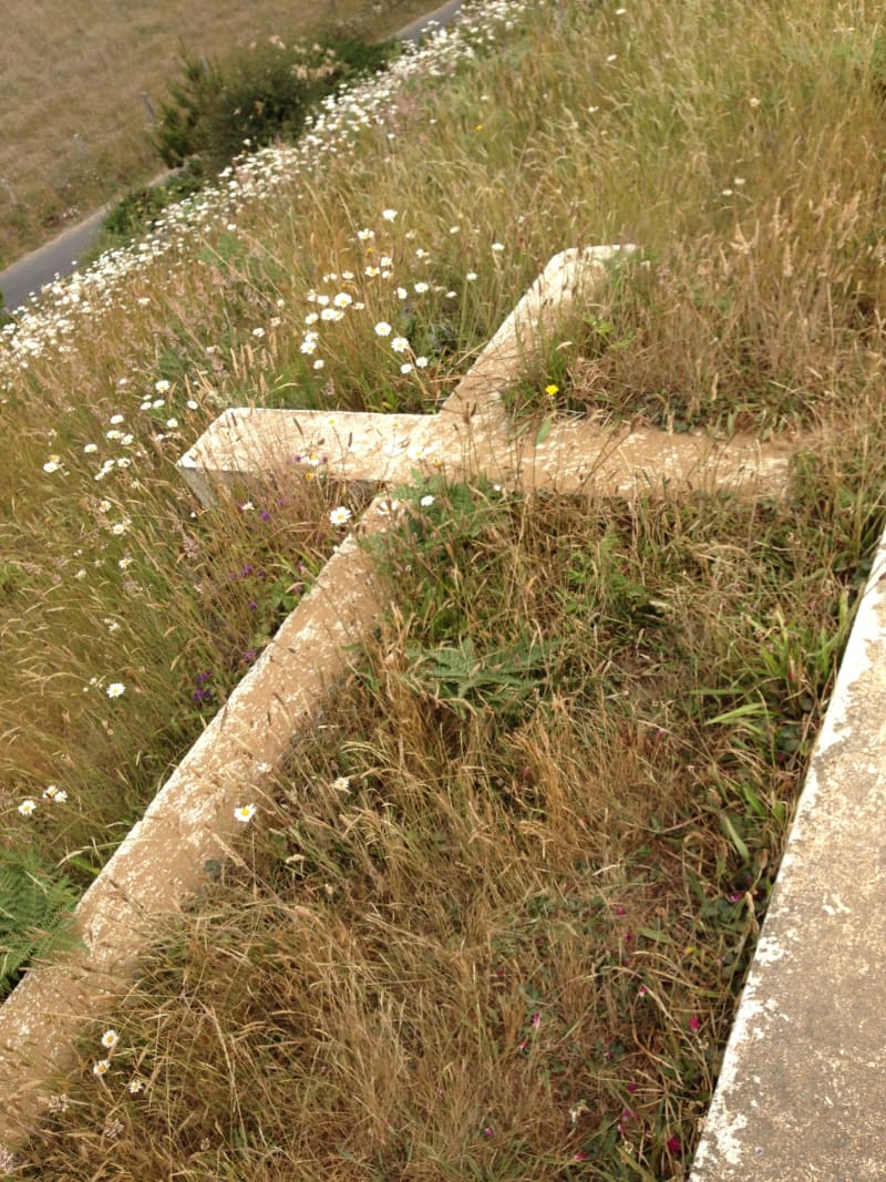 The original cross fell in an earthquake. It now lies next to the new cross.