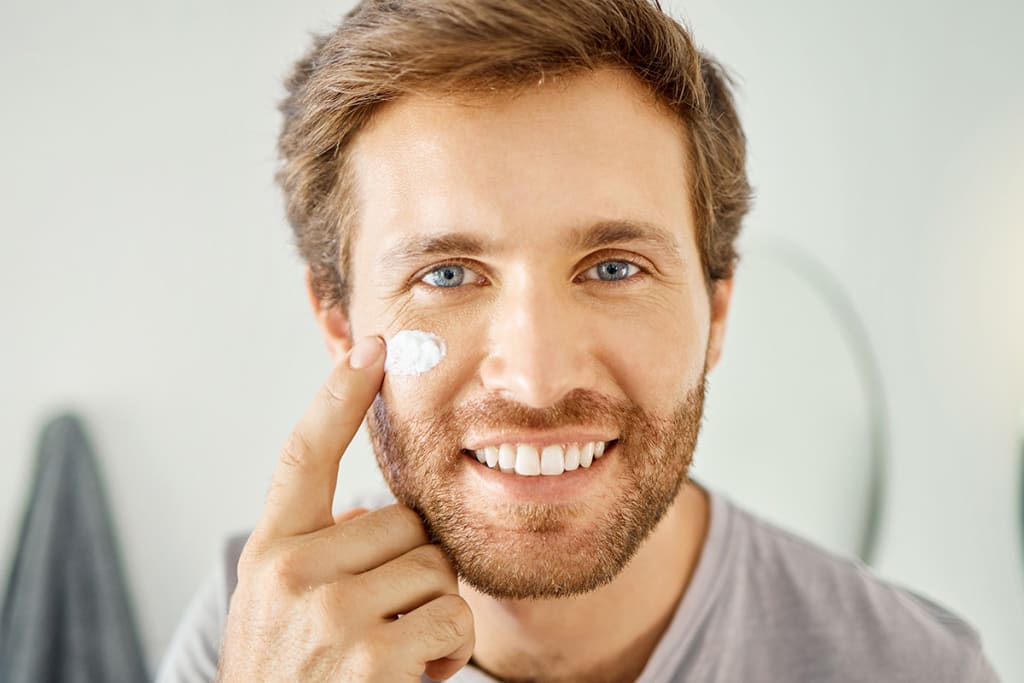 Portrait photo of man applying skincare onto face