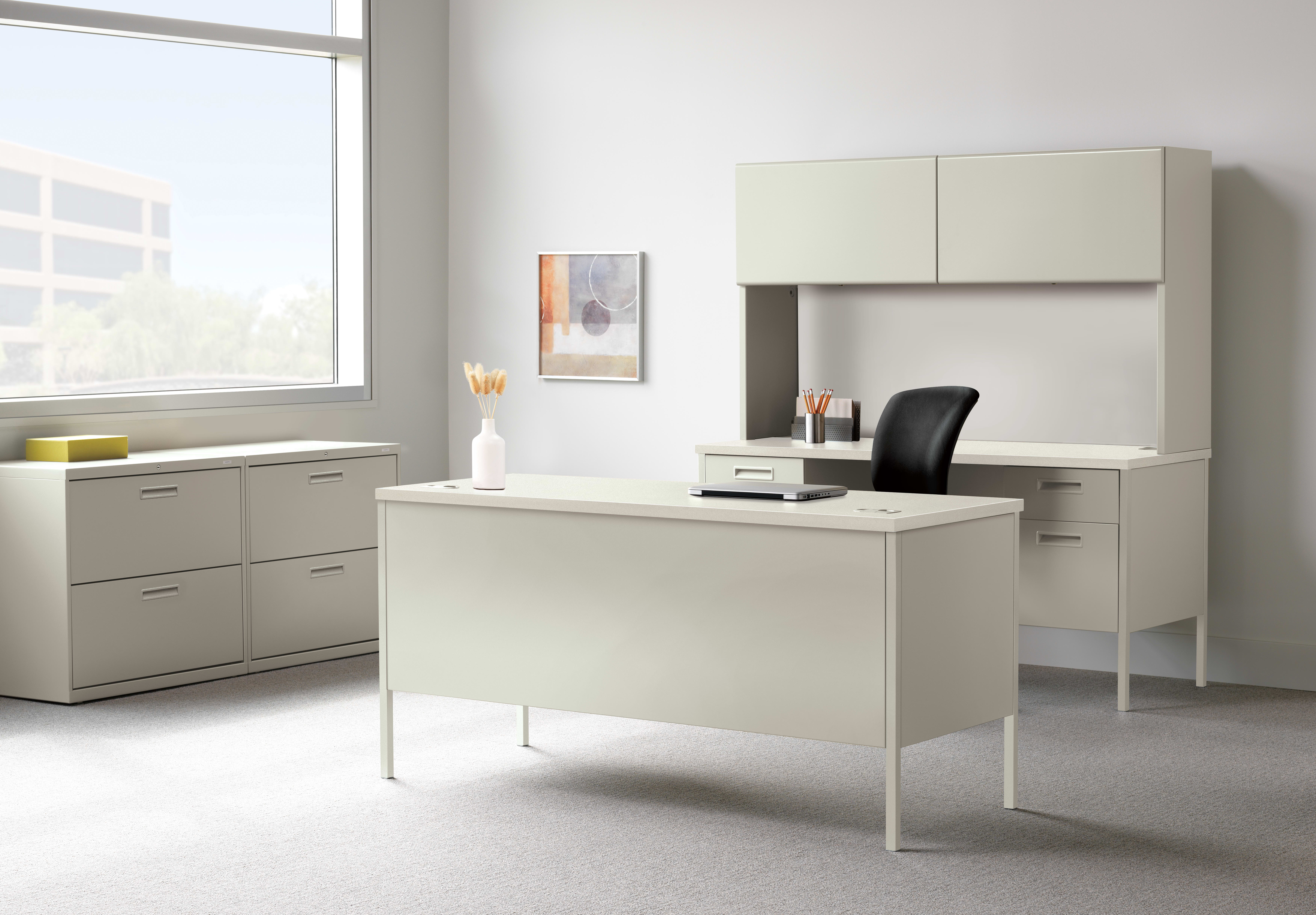 A modern, minimalist office space with a white desk, cabinets, and a framed artwork on the wall, set against a bright, natural light-filled background.