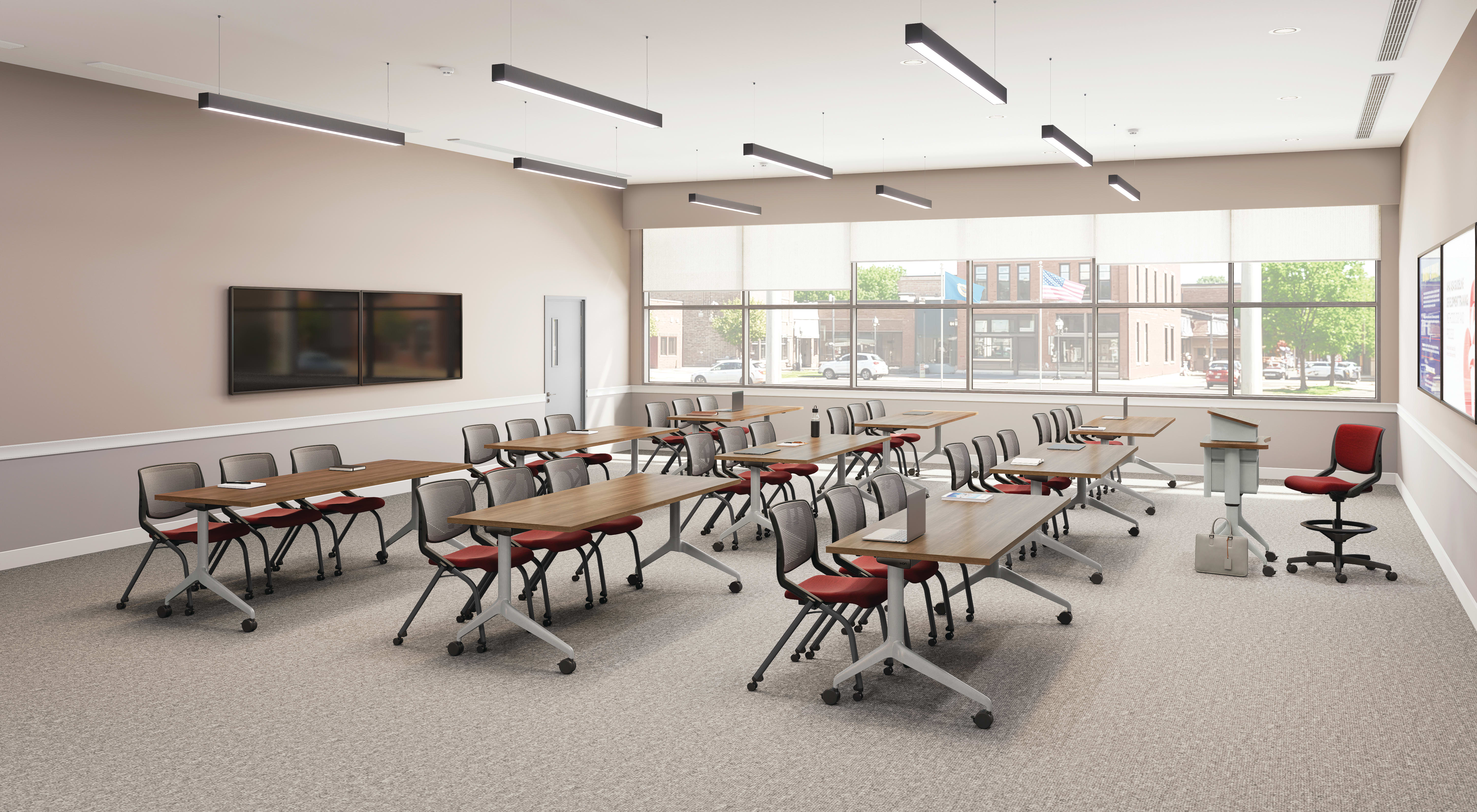 Flexible classroom with movable tables and chairs, large windows, ceiling lights, wall-mounted displays, and instructor podium in a bright, modern space.