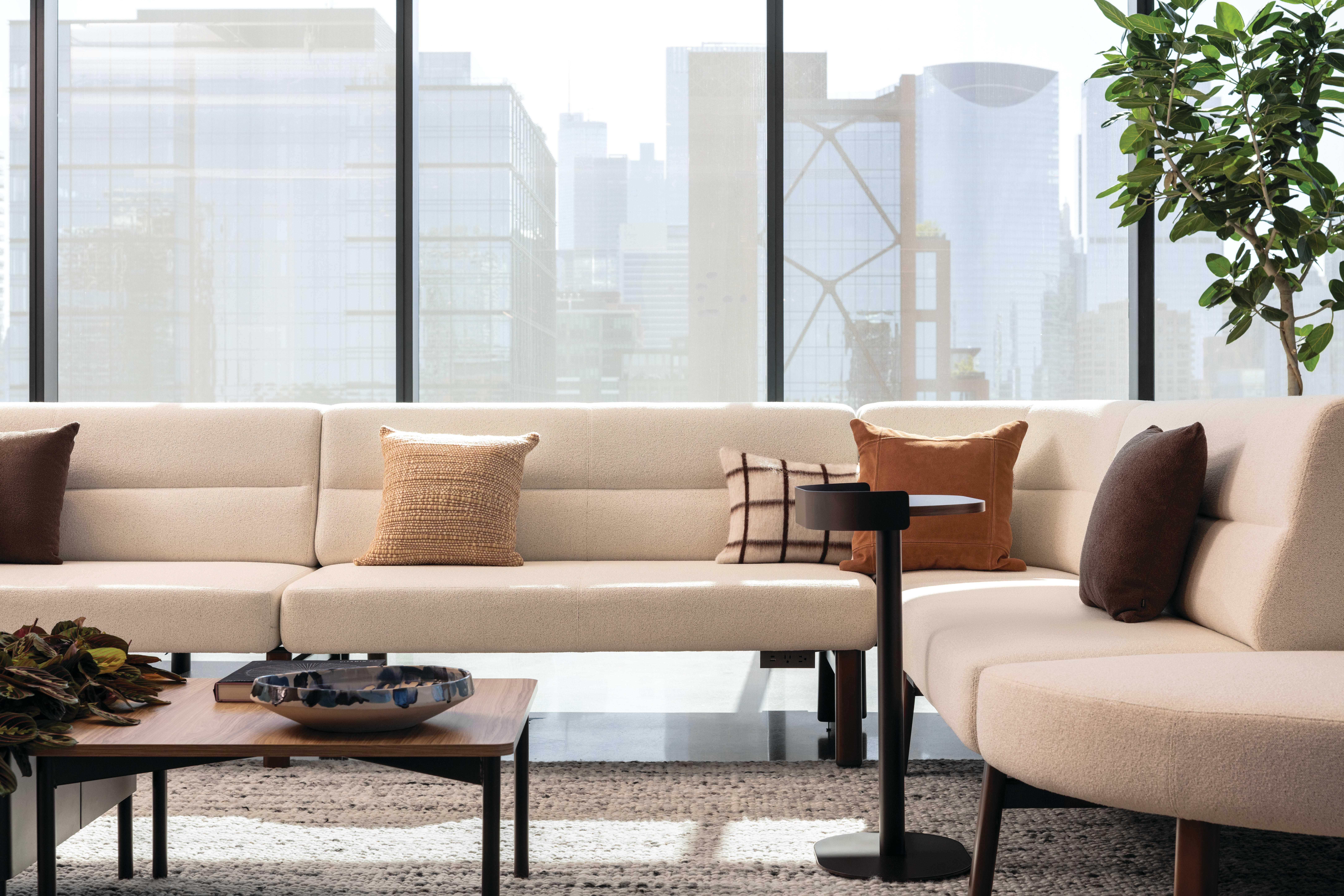 Upholstered modular sofa with low profile and soft cushions, paired with rectangular wood coffee table on slim legs for lounge seating.