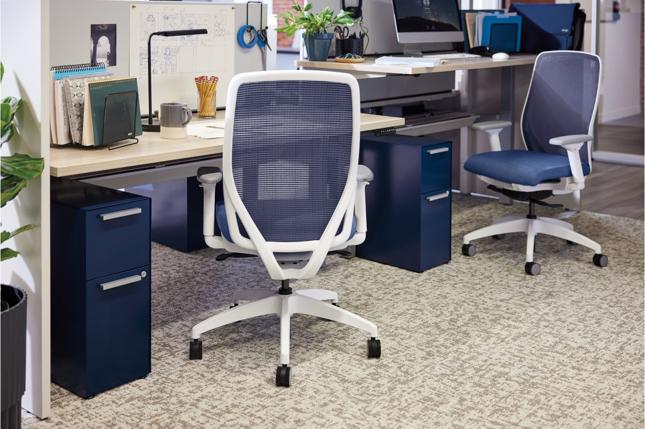 A modern and organized office workspace with a desk, computer, and various office supplies and equipment, including a comfortable-looking office chair.