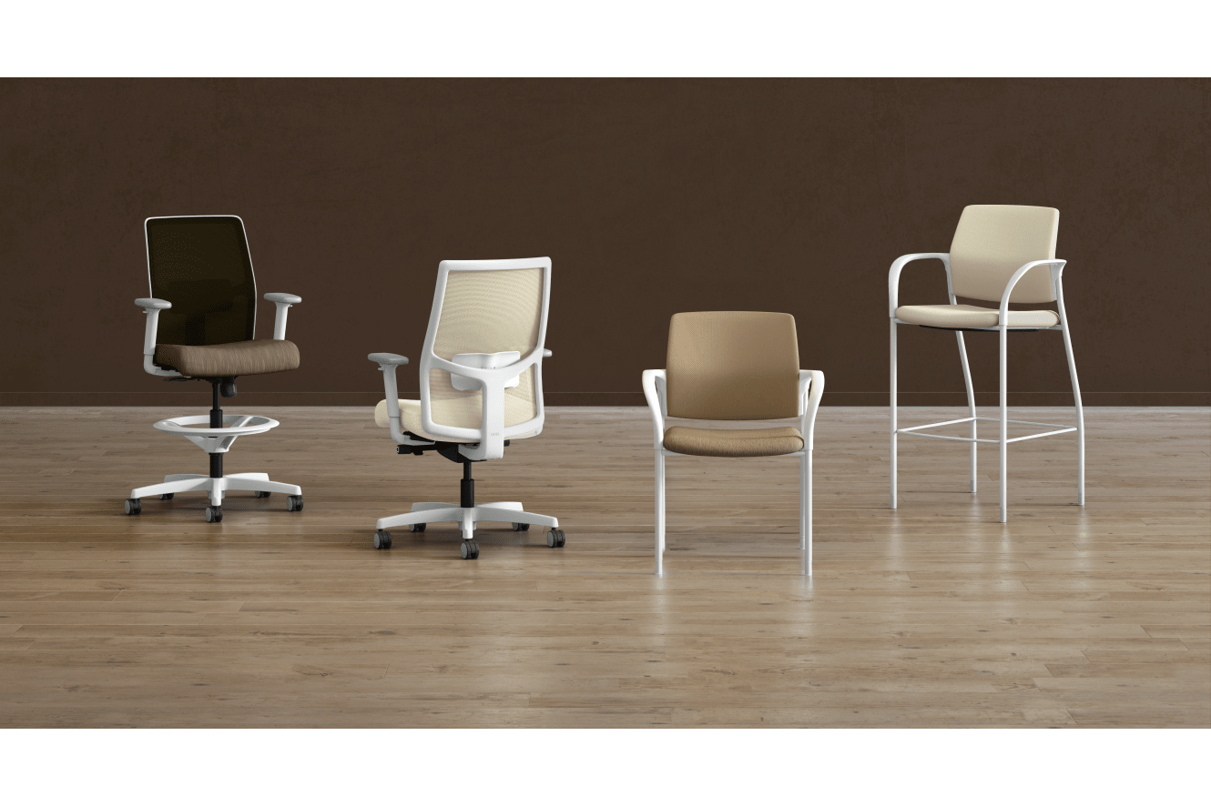 A collection of modern office chairs in various styles and colors, arranged on a wooden floor against a plain brown background.