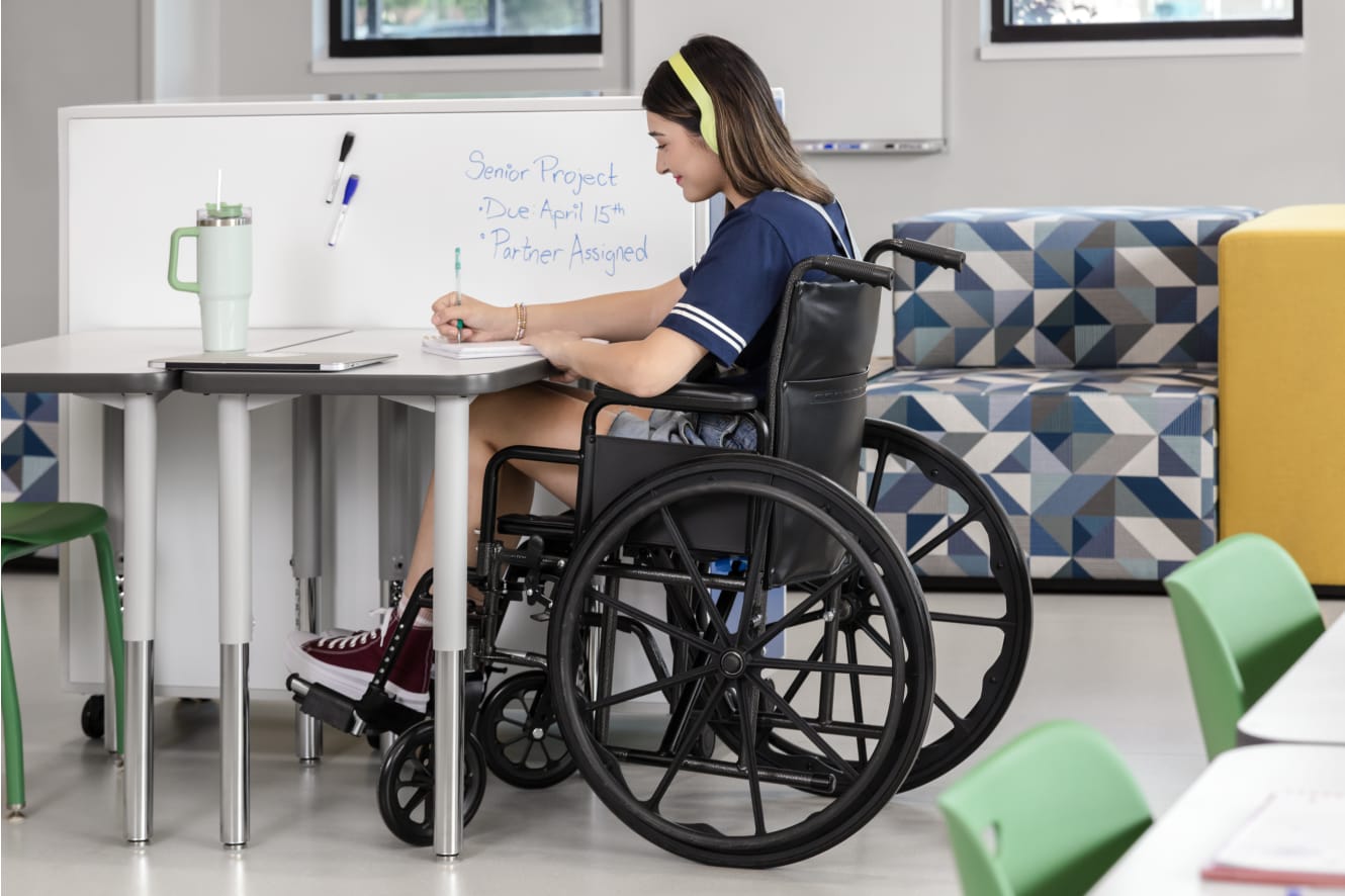 One student in a wheelchair at a Build desk next to the whiteboard back of a Class-ifi storage unit.