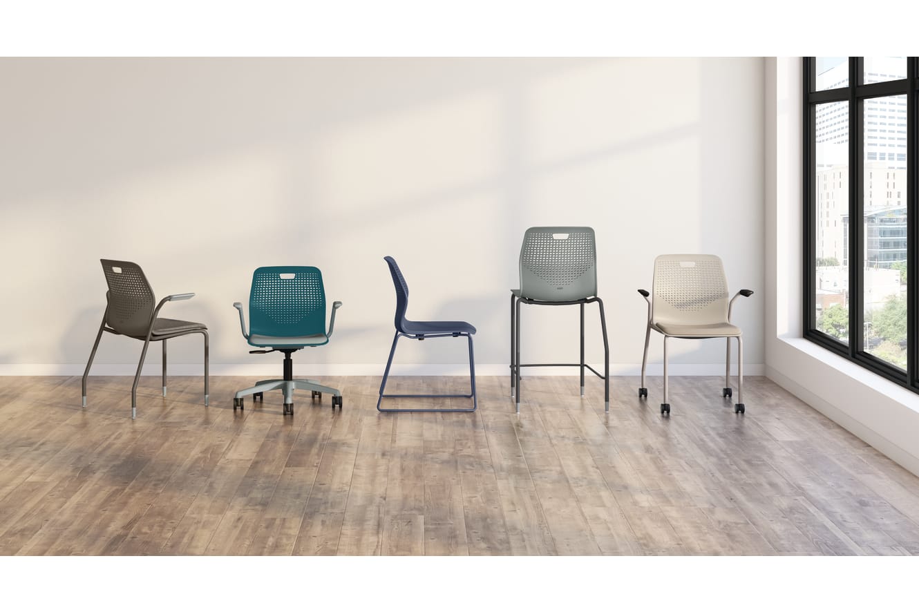 A variety of modern, minimalist chairs in different colors and designs are arranged in an empty, well-lit room with a wooden floor and a large window in the background.