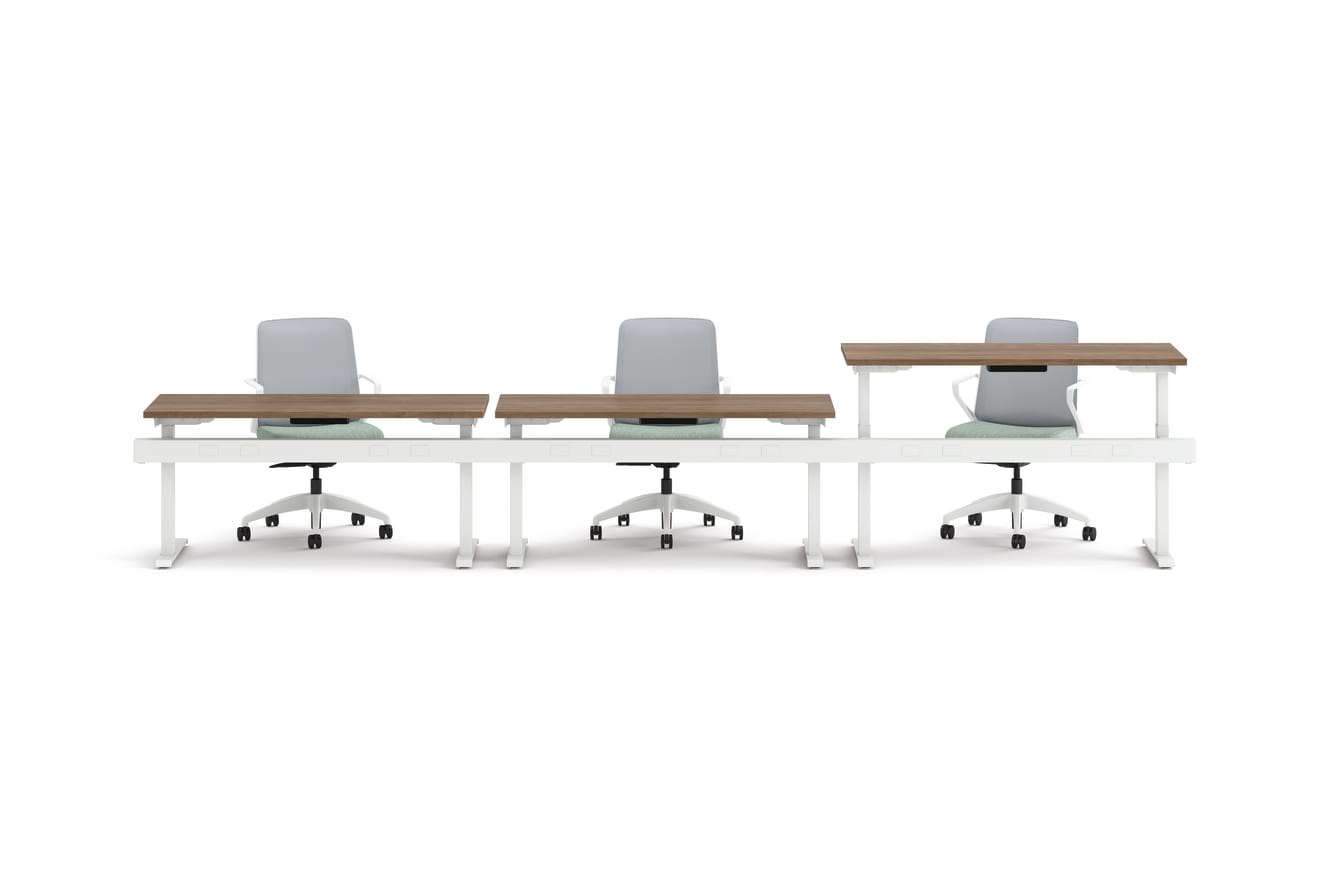 Three ergonomic office chairs positioned behind adjustable-height desks with white frames and wooden tops.