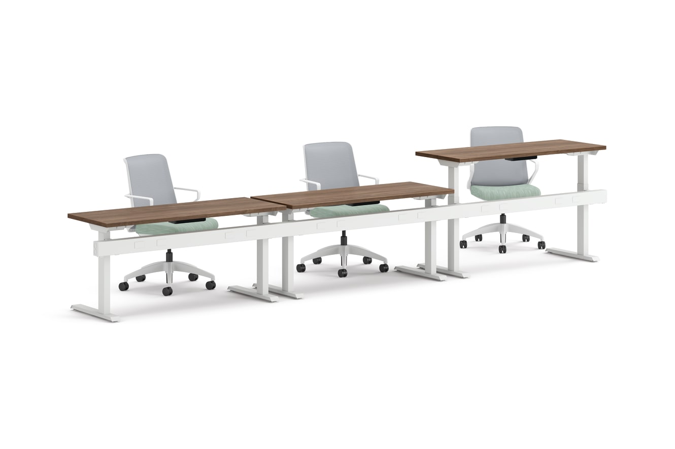 Three ergonomic office chairs positioned behind adjustable-height desks with white frames and wooden tops.
