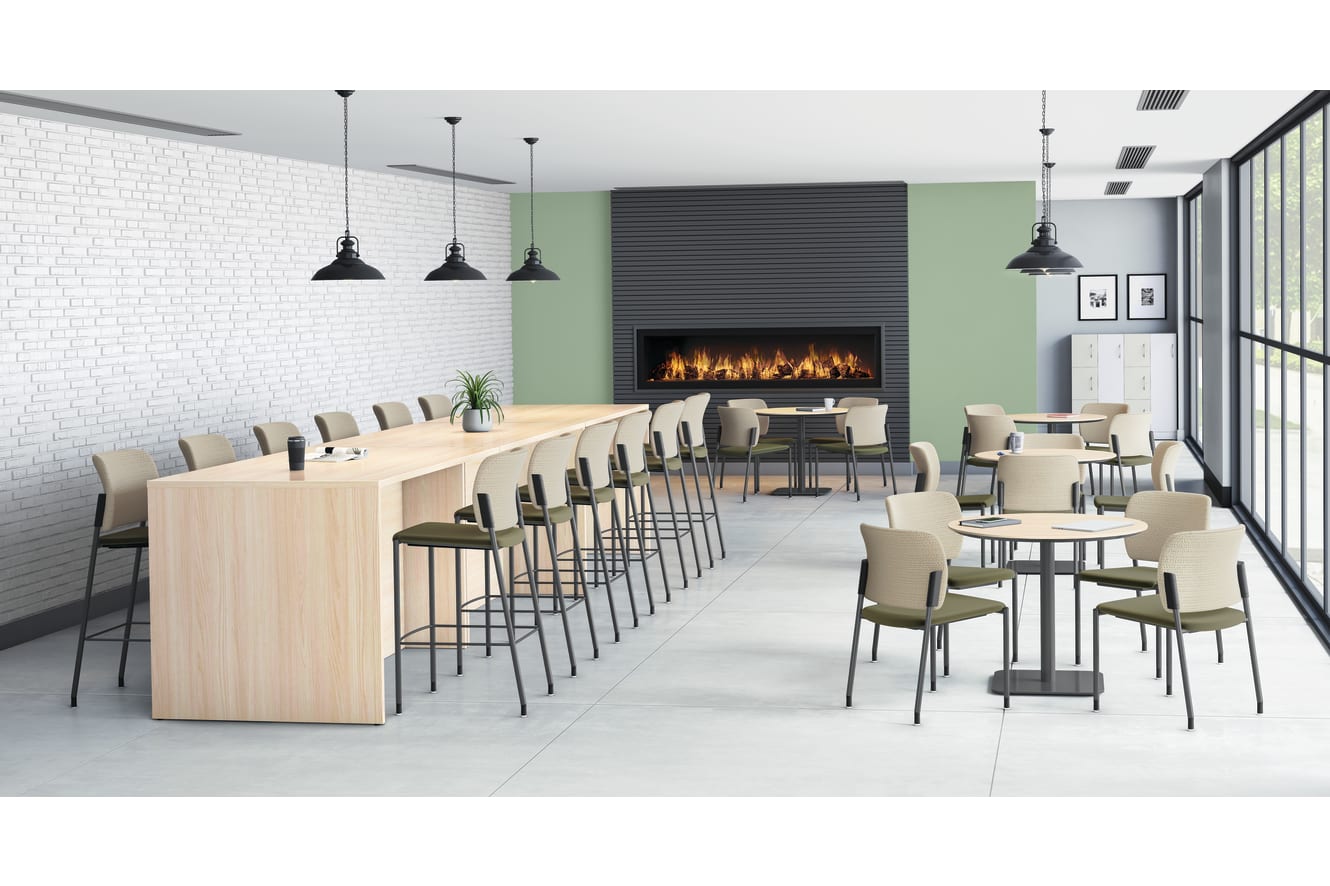 Modern cafeteria with long wooden counter and barstools, round tables with chairs, pendant lights, and built-in fireplace against green and gray accent wall