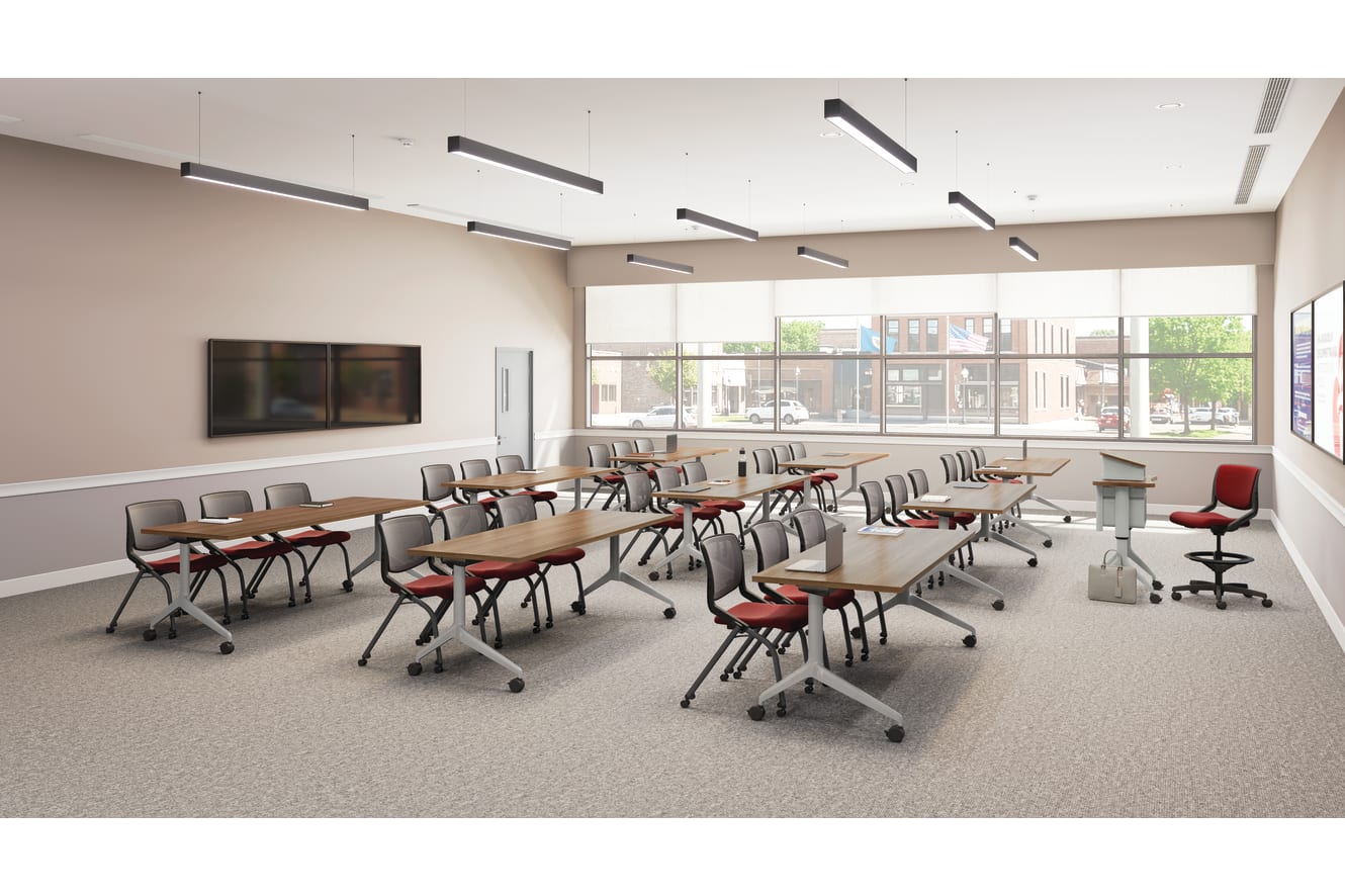 Flexible classroom with movable tables and chairs, large windows, ceiling lights, wall-mounted displays, and instructor podium in a bright, modern space.