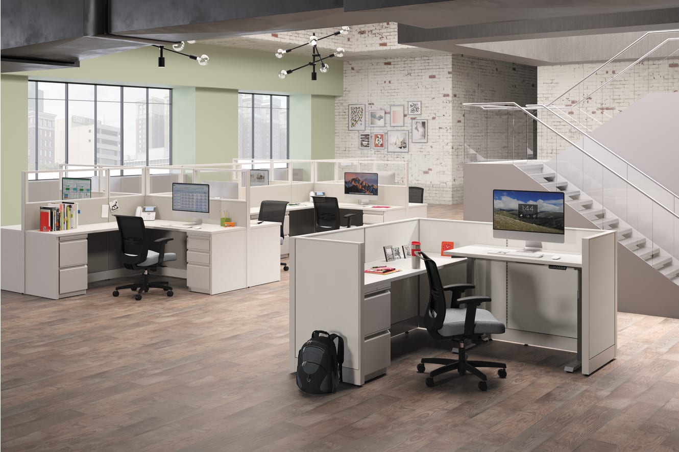 A modern, open-concept office space with cubicles, desks, and various office equipment and decor, including computers, monitors, and personal items.