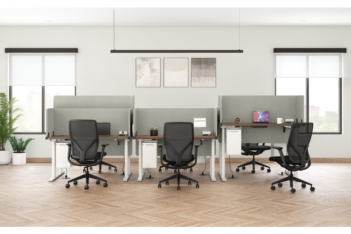 A modern and minimalist office space with white walls, wooden floors, and sleek black office chairs arranged around desks with potted plants and artwork on the walls.