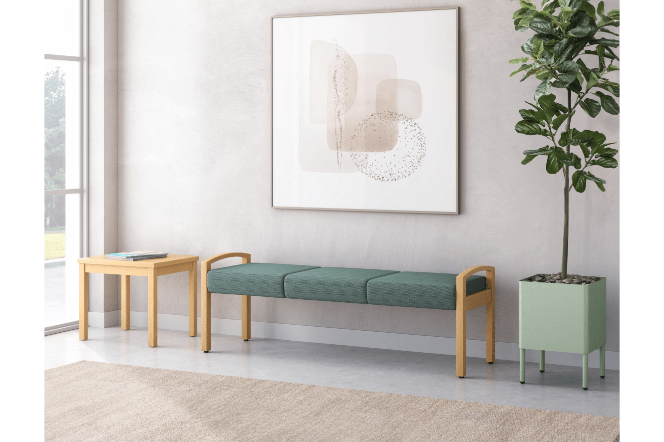A minimalist living room with a framed abstract artwork, a wooden bench with green cushions, and a potted plant, all set against a bright and airy background.