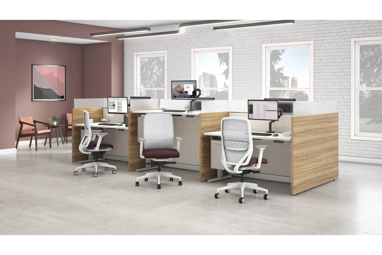 Modern office workstation layout with wood panel cubicles, fabric privacy screens, adjustable desks, ergonomic task chairs, and large windows with city views.