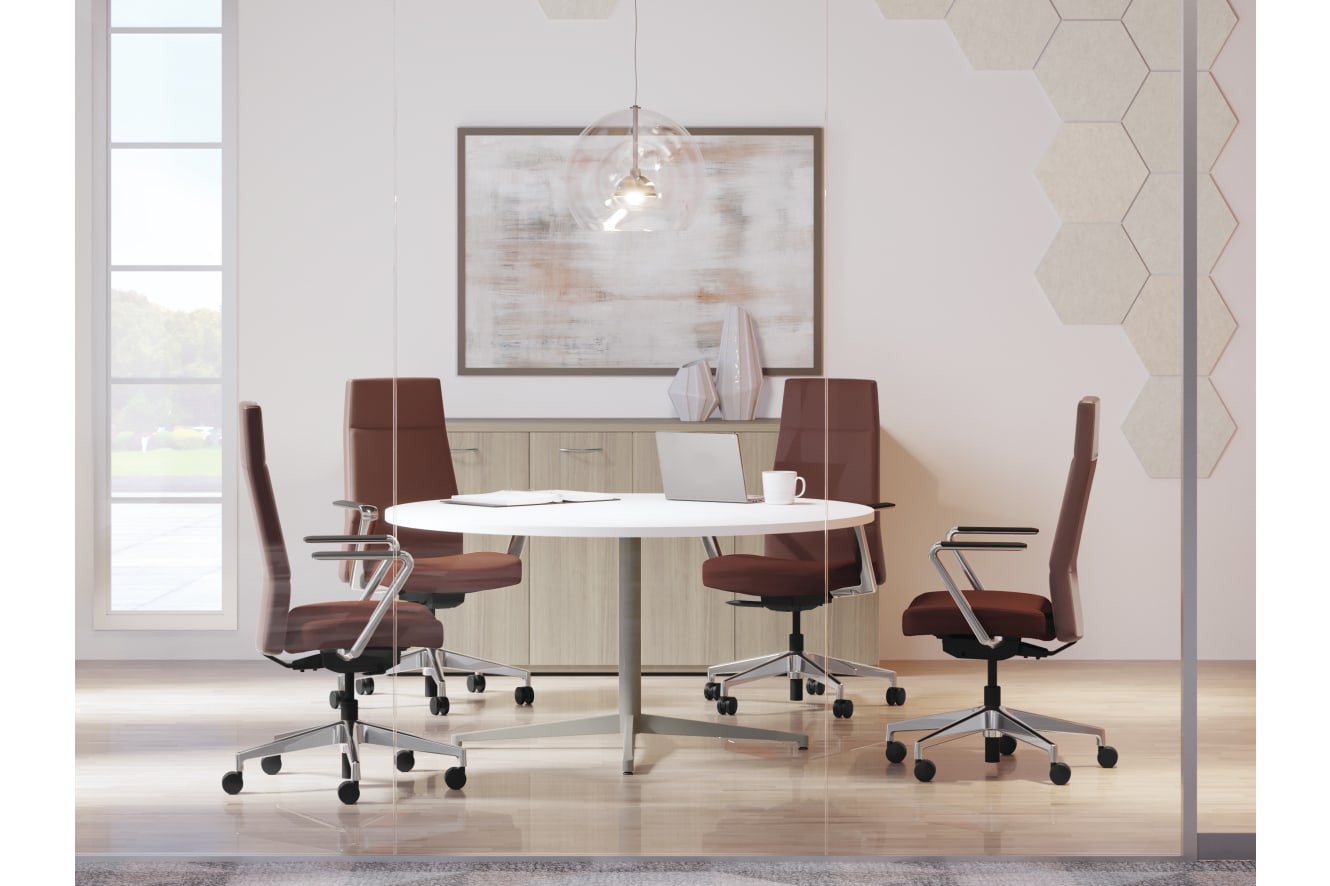 A modern, minimalist office space with a round white table, brown leather chairs, and a large framed artwork on the wall.