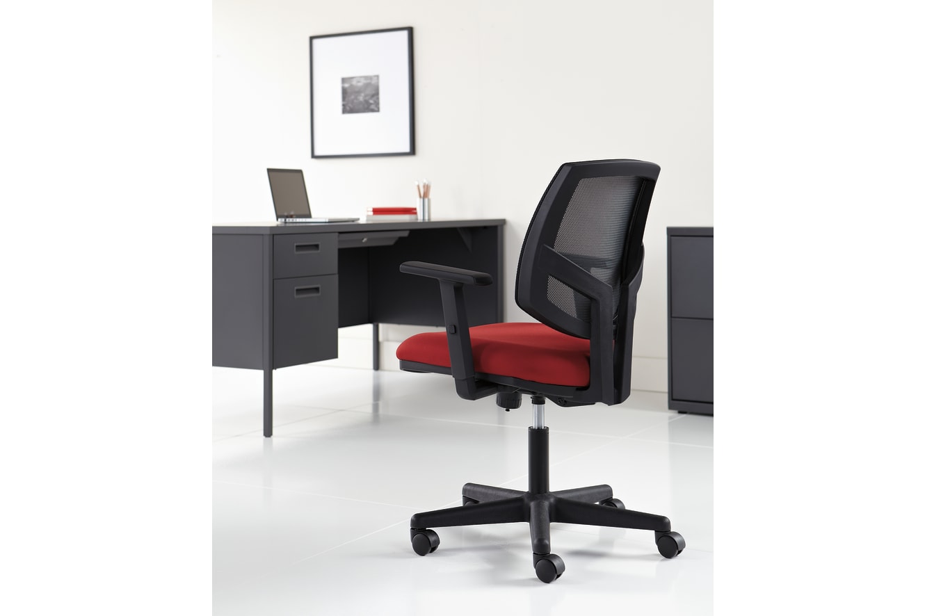 A modern, minimalist office setup with a black desk, a laptop, and a red and black office chair on a white floor, with a framed artwork on the wall in the background.