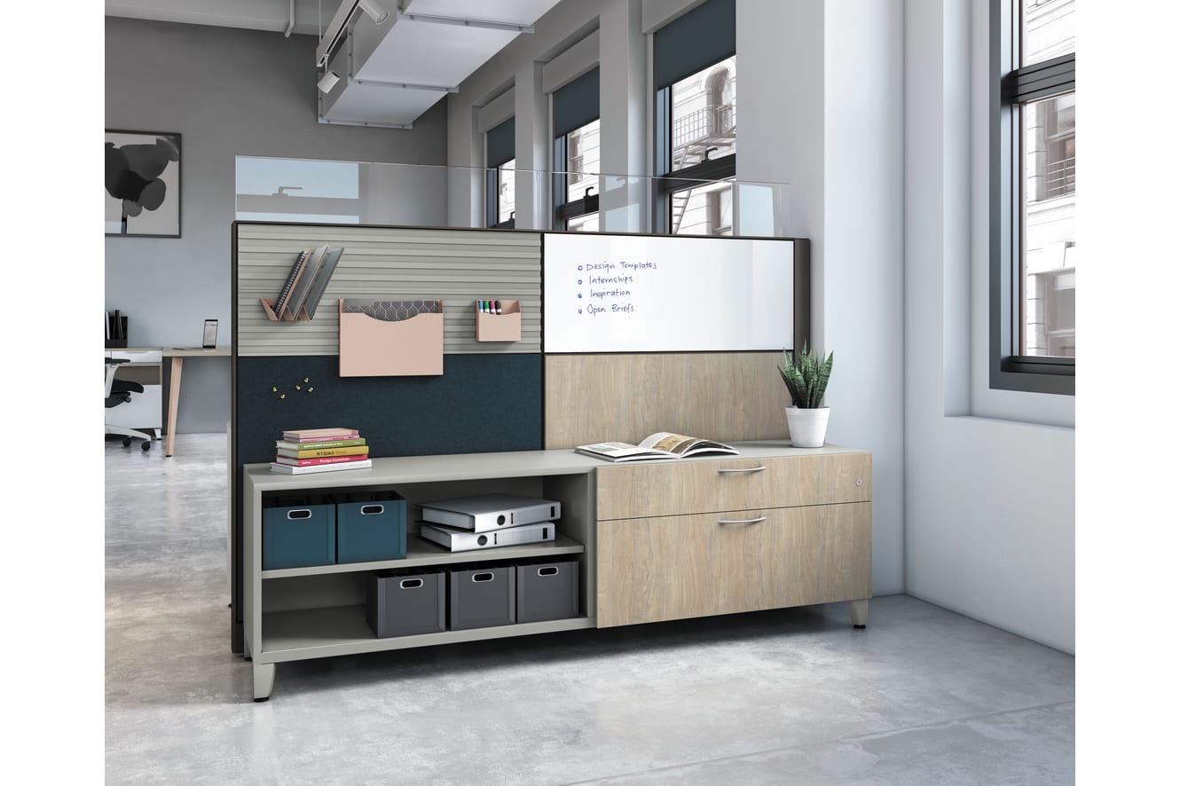 A modern, minimalist office space with a whiteboard, shelves, and storage units, set against a backdrop of large windows and a concrete floor.