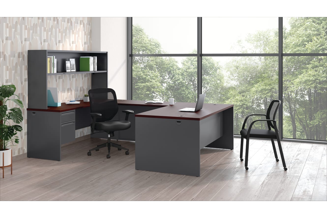 A modern and minimalist home office space with a dark-colored desk, shelving unit, and a chair in the foreground, set against a large window overlooking a lush, green outdoor environment.