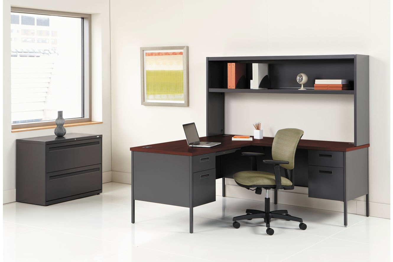 A modern and minimalist home office setup with a black desk, shelving unit, and a comfortable office chair in a bright and airy room.
