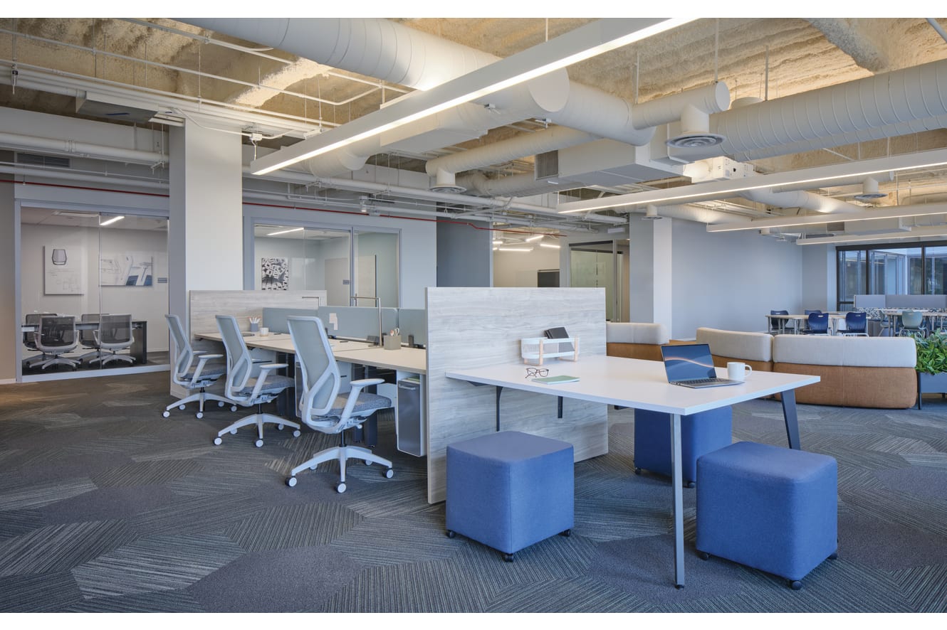 Empower benching with Universal screens and Gallery panels shown with Flexion task seating with Fuse storage. Flock seating mini cubes on the end of the workstation.